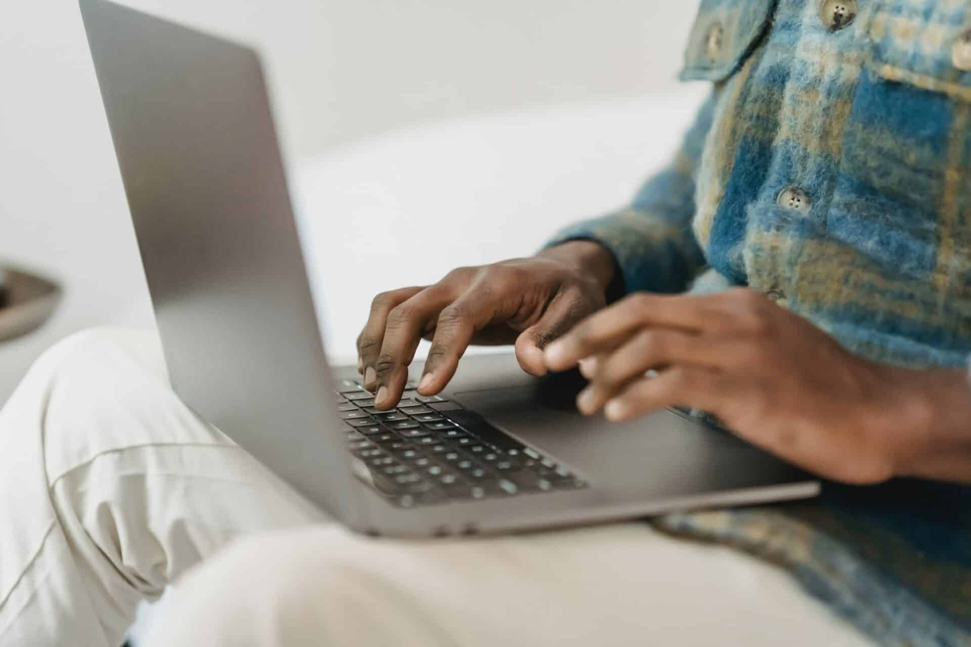 someone sitted with a laptop on their laps surfing the Internet