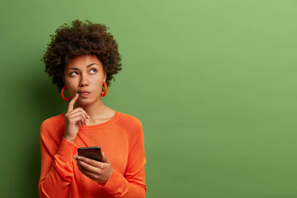 Nigeria has a new data protection enforcing body; here’s why you should care 1 photo pretty ethnic woman ponders how answer question thinks deeply about something uses modern mobile phone tries made up good message keeps index finger near lips stands indoor
