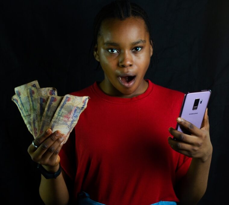 Eastern and Southern African regulator probes Airtel Money 3 Lady holding smartphone and cash looking shocked