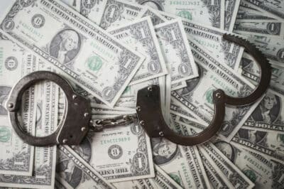 Several dollar notes and a handcuff, indication fraud