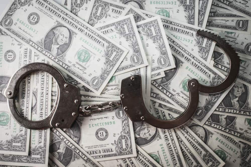 Binance executive sues EFCC over unfair detention 2 Several dollar notes and a handcuff, indication fraud