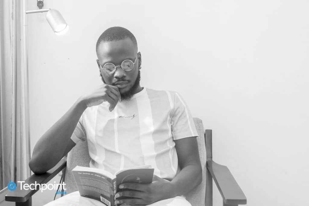 Meet Daniel Orubo, the creative storyteller behind Zikoko and Piggyvest's success stories 3 An image of Daniel Orubo. Head of content and content strategy, Piggyvest sitting beside a lamp and reading a book