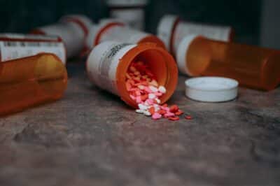 Several bottled drugs are on the floor, one of which is open and contains many medications