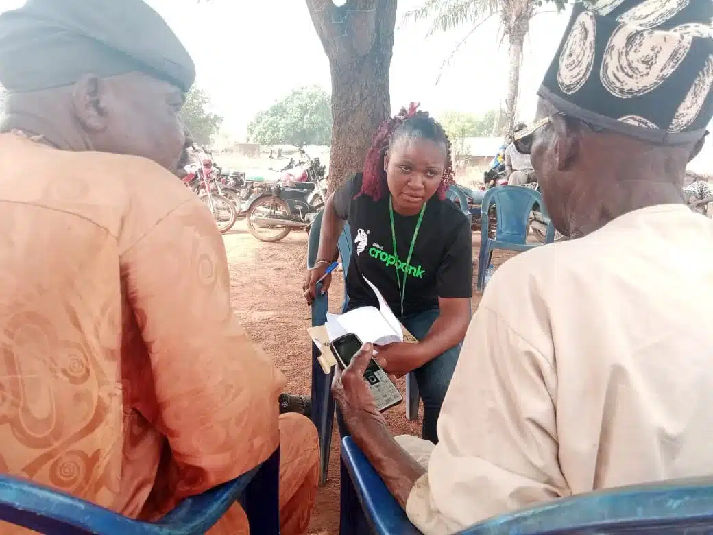 A representative of Zebra CropBank talking to two farmers
