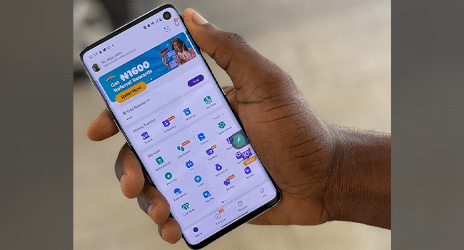 Hand holding a phone displaying PalmPay app