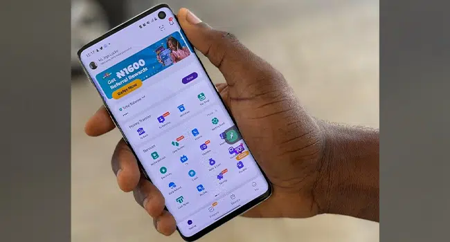 Hand holding a phone displaying PalmPay app